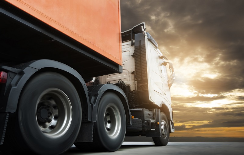 Semi truck trailer driving on road at sunset sky. Cargo freight truck, Logistics and transportation.